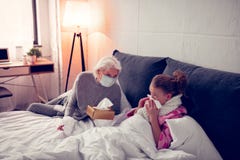 Flicka som använder servetter, medan ha den rinnande näsan nära hennes att bry sig farmor arkivfoto Flicka som använder servetter, medan ha den rinnande näsan nära hennes att bry sig farmor arkivfoto