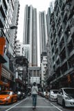 Flicka som går bland högväxta bostads- byggnader och dyra bilar i Hong Kong China fotografering för bildbyråer Flicka som går bland högväxta bostads- byggnader och dyra bilar i Hong Kong China fotografering för bildbyråer