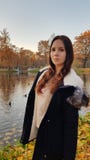 Flickaflicka i ett blått höstomslag på bakgrunden av sjön royaltyfria bilder Flickaflicka i ett blått höstomslag på bakgrunden av sjön royaltyfria bilder