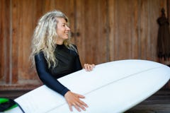 Flickan med surfingbrädan sitter på verandamoment av strandvillan arkivfoto Flickan med surfingbrädan sitter på verandamoment av strandvillan arkivfoto
