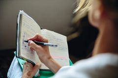 Flickan skriver den aktuella affären på böckerna arkivfoton Flickan skriver den aktuella affären på böckerna arkivfoton