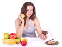 Flickan väljer mellan ett äpple och en kaka arkivbild Flickan väljer mellan ett äpple och en kaka arkivbild