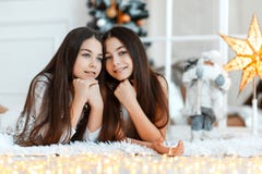 Flickor kopplar samman framme av gran-trädet Helgdagsafton för ` s för nytt år Jul Hemtrevlig ferie på gran-trädet med ljus fotografering för bildbyråer Flickor kopplar samman framme av gran-trädet Helgdagsafton för ` s för nytt år Jul Hemtrevlig ferie på gran-trädet med ljus fotografering för bildbyråer