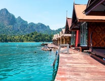 Floating wooden houses on a lake with mountains and rain forest in the background during a sunny day at Ratchaprapha Dam stock photos Floating wooden houses on a lake with mountains and rain forest in the background during a sunny day at Ratchaprapha Dam stock photos