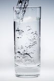 Flusso di versamento dell'acqua minerale in un vetro Immagini Stock Flusso di versamento dell'acqua minerale in un vetro Immagini Stock