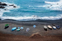 Flyg- sikt av färgrika fartyg på en svart sandstrand i Lanzarote, kanariefågelöar, Spanien royaltyfri foto Flyg- sikt av färgrika fartyg på en svart sandstrand i Lanzarote, kanariefågelöar, Spanien royaltyfri foto
