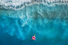 Flyg- sikt av simning för ung kvinna på den rosa badcirkeln royaltyfri fotografi Flyg- sikt av simning för ung kvinna på den rosa badcirkeln royaltyfri fotografi