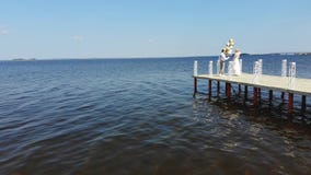 Flyg- video, h?rliga nygift personpar, brud och brudgum som utomhus dansar, p? en h?rlig pir, mot det bl?a havet och lager videofilmer Flyg- video, h?rliga nygift personpar, brud och brudgum som utomhus dansar, p? en h?rlig pir, mot det bl?a havet och lager videofilmer