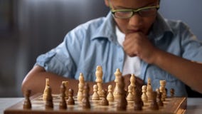 Focused school boy thinking of attacking and capturing opponent chess pieces royalty free stock photo Focused school boy thinking of attacking and capturing opponent chess pieces royalty free stock photo