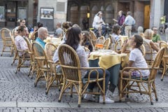 Folket sitter på små tabeller i gatakafé royaltyfri fotografi Folket sitter på små tabeller i gatakafé royaltyfri fotografi