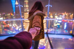 Follow me couple traveling in oriental pearl TV tower. Woman red hair in orange jacket holding man by hand going to night view of city in shanghai. Traveling royalty free stock images Follow me couple traveling in oriental pearl TV tower. Woman red hair in orange jacket holding man by hand going to night view of city in shanghai. Traveling royalty free stock images