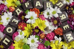 Fond féminin de cadeau avec un grand choix de fleurs et d'inscription colorées de chocolat dans les félicitations russes Vue supé Images stock