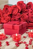 Fondo festivo al día de tarjeta del día de San Valentín Un ramo de rosas rojas, de una caja de regalo y de una vela en forma de c fotos de archivo Fondo festivo al día de tarjeta del día de San Valentín Un ramo de rosas rojas, de una caja de regalo y de una vela en forma de c fotos de archivo