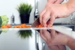 Food, family, cooking and people concept - Man chopping a carrot on cutting board with knife in kitchen stock images Food, family, cooking and people concept - Man chopping a carrot on cutting board with knife in kitchen stock images