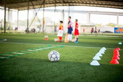 Football , Marker Cone And Ladder Drills On Green Artificial Turf With Blurry Kid Soccer Players Are Training Royalty Free Stock Photos