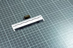 The forensic ruler rests on a laboratory checkered background next to the shot cartridge for the pistol. Copyspace. royalty free stock image The forensic ruler rests on a laboratory checkered background next to the shot cartridge for the pistol. Copyspace. royalty free stock image