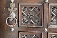 Forged metal lock handle in vintage wooden door with printed carved pattern, vintage stock image Forged metal lock handle in vintage wooden door with printed carved pattern, vintage stock image