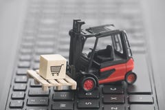 Forklift with shopping cart graphic on wooden block over laptop keyboard stock image Forklift with shopping cart graphic on wooden block over laptop keyboard stock image