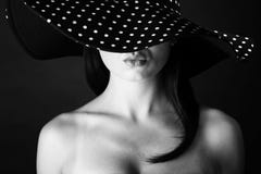 Forme o retrato de uma mulher com os bordos preto e branco do chapéu e da lota dos pontos imagem de stock Forme o retrato de uma mulher com os bordos preto e branco do chapéu e da lota dos pontos imagem de stock
