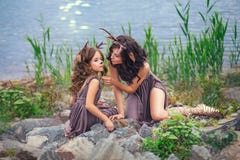 A foto de família da mãe e da criança, faunos na costa de um grande lago está sentando-se em pedras, caráteres do conto de fadas, imagens de stock A foto de família da mãe e da criança, faunos na costa de um grande lago está sentando-se em pedras, caráteres do conto de fadas, imagens de stock