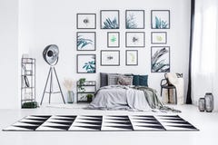 Foto real de una cama que se coloca entre una lámpara y una silla en un bri imagen de archivo libre de regalías Foto real de una cama que se coloca entre una lámpara y una silla en un bri imagen de archivo libre de regalías