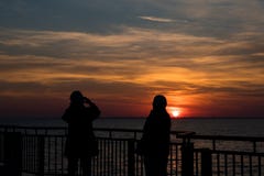 Foto van de zonsondergang met het silhouet van twee dames stock fotografie Foto van de zonsondergang met het silhouet van twee dames stock fotografie