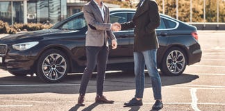 Foto von zwei intelligenten eleganten M?nnern, die ein Abkommen ?ber Auto haben lizenzfreies stockbild Foto von zwei intelligenten eleganten M?nnern, die ein Abkommen ?ber Auto haben lizenzfreies stockbild