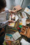 Fotografando o processo de tirar imagens na aquarela Telefone celular da terra arrendada da moça do artista e fotos da tomada imagens de stock Fotografando o processo de tirar imagens na aquarela Telefone celular da terra arrendada da moça do artista e fotos da tomada imagens de stock