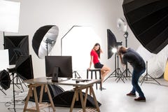Fotografo e modello grazioso che lavorano nello studio moderno di illuminazione immagini stock Fotografo e modello grazioso che lavorano nello studio moderno di illuminazione immagini stock