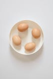Four fresh brown eggs lie on a white plate on a light background. Space to copy the inscriptions and design royalty free stock photo Four fresh brown eggs lie on a white plate on a light background. Space to copy the inscriptions and design royalty free stock photo