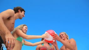 Four friends playing with an inflatable beach ball