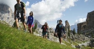 Four friends walking along wild hiking trail path. Group of friends people summer adventure journey in mountain nature