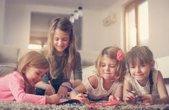 Four girls lying on the floor. Four girls lying on the floor and write their homework. Close up image of little girls Royalty Free Stock Photography Four girls lying on the floor. Four girls lying on the floor and write their homework. Close up image of little girls Royalty Free Stock Photography