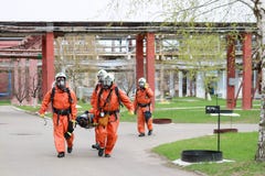 Four professional firefighter firefighters in orange protective fireproof suits, white helmets and gas masks carry the injured per royalty free stock images Four professional firefighter firefighters in orange protective fireproof suits, white helmets and gas masks carry the injured per royalty free stock images