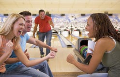 Four young adults cheering in a bowling alley