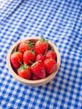 Fraise dans une tasse en bois sur la texture à carreaux bleue et blanche de tissu images stock Fraise dans une tasse en bois sur la texture à carreaux bleue et blanche de tissu images stock