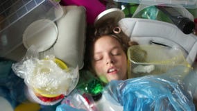Framsidan av ett barn i en hög av plast- avfalls Plast- förorening av planeten jorda en kontakt saven lager videofilmer Framsidan av ett barn i en hög av plast- avfalls Plast- förorening av planeten jorda en kontakt saven lager videofilmer