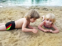 Fratello e sorella che si rilassano sulla sabbia vicino al lago immagini stock Fratello e sorella che si rilassano sulla sabbia vicino al lago immagini stock