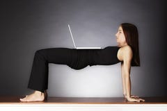 Frau in der Yogabrückenhaltung mit Laptop. Lizenzfreie Stockbilder Frau in der Yogabrückenhaltung mit Laptop. Lizenzfreie Stockbilder