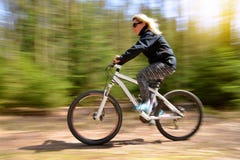 Frau, die eine Mountainbike auf einen Waldweg reitet lizenzfreie stockfotografie Frau, die eine Mountainbike auf einen Waldweg reitet lizenzfreie stockfotografie