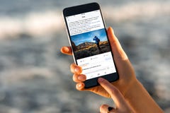 Frau, die Facebook-Nachrichten mit neuem iPhone aufpasst lizenzfreie stockbilder Frau, die Facebook-Nachrichten mit neuem iPhone aufpasst lizenzfreie stockbilder