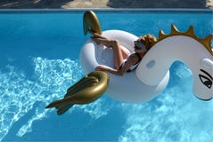 Frau, die im Luxusswimmingpoolurlaubshotel auf dem großen aufblasbaren Einhorn schwimmt Pegasus-Floss sich entspannt lizenzfreie stockfotografie Frau, die im Luxusswimmingpoolurlaubshotel auf dem großen aufblasbaren Einhorn schwimmt Pegasus-Floss sich entspannt lizenzfreie stockfotografie