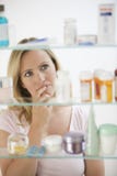 Frau, die im Medizin-Kabinett schaut lizenzfreies stockbild Frau, die im Medizin-Kabinett schaut lizenzfreies stockbild