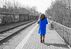 Frau im blauen Mantel geht nahe der Eisenbahn lizenzfreie stockfotografie Frau im blauen Mantel geht nahe der Eisenbahn lizenzfreie stockfotografie