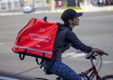 Frau im Fahrrad, das für Rappi-Nahrungsmittelzustelldienst arbeitet lizenzfreie stockfotos Frau im Fahrrad, das für Rappi-Nahrungsmittelzustelldienst arbeitet lizenzfreie stockfotos