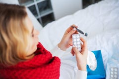Frau mit dem Grippevirus, das im Bett liegt, misst sie ihre Temperatur mit einem Thermometer stockbilder Frau mit dem Grippevirus, das im Bett liegt, misst sie ihre Temperatur mit einem Thermometer stockbilder