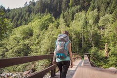 Frau mit einem Rucksack gehend auf eine Brücke in den Wald lizenzfreie stockfotografie Frau mit einem Rucksack gehend auf eine Brücke in den Wald lizenzfreie stockfotografie