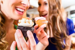 Frauen, die Muffins während Kaffeetrinken essen lizenzfreie stockbilder Frauen, die Muffins während Kaffeetrinken essen lizenzfreie stockbilder