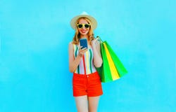 Frauen-Holding Smartphone des Porträts glücklicher lächelnder mit Einkaufstaschen im bunten T-Shirt, Sommerstrohhut, Sonnenbri stockbilder Frauen-Holding Smartphone des Porträts glücklicher lächelnder mit Einkaufstaschen im bunten T-Shirt, Sommerstrohhut, Sonnenbri stockbilder