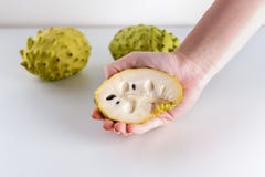 Frauen-Hände, die Annona-Frucht auf weißem Hintergrund halten lizenzfreies stockfoto Frauen-Hände, die Annona-Frucht auf weißem Hintergrund halten lizenzfreies stockfoto